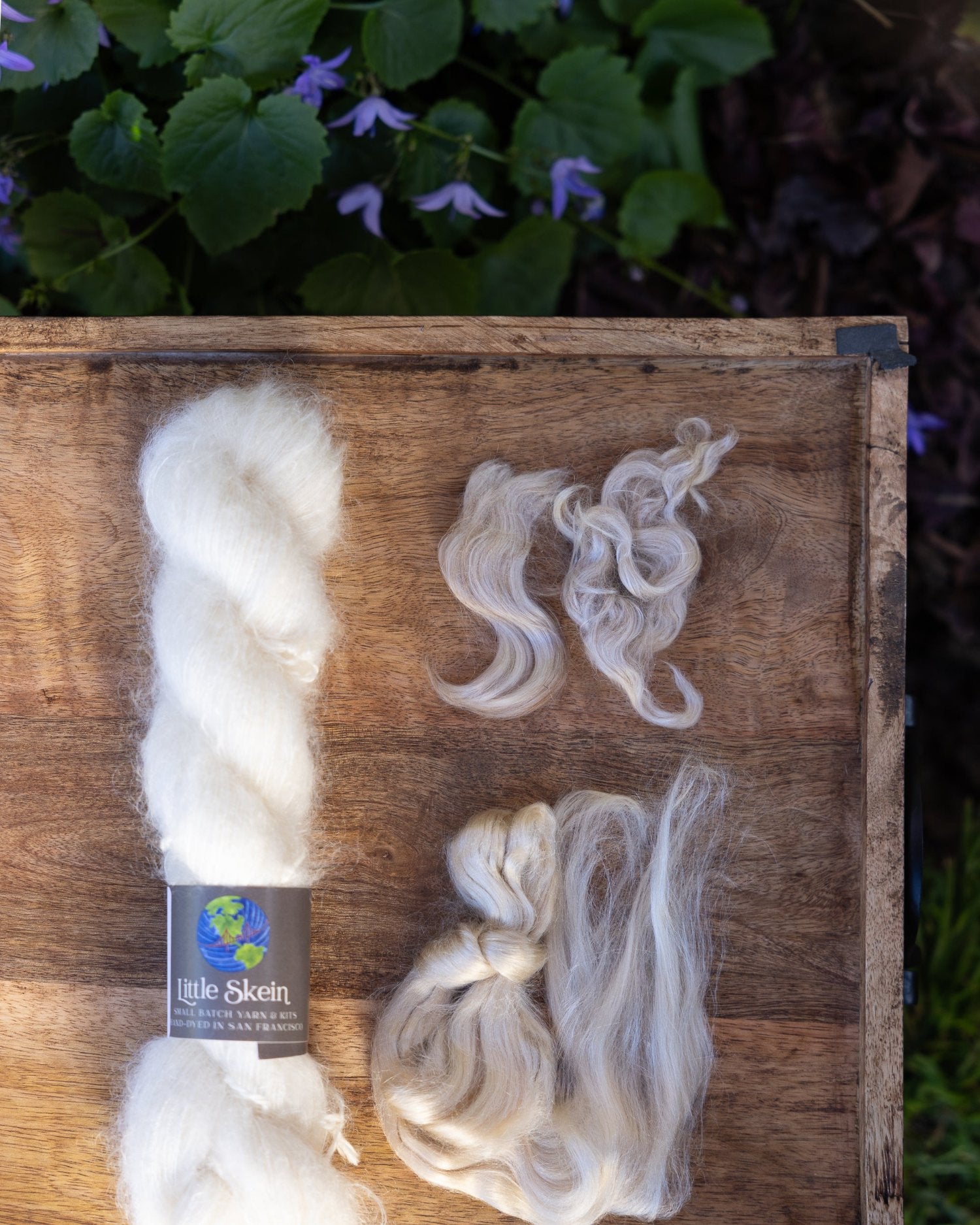 Unwound skein of yarn with representative samples of the fiber contained in the yarn: mohair wool and silk