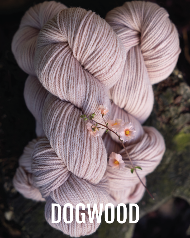 A stack of hand-dyed worsted weight  yarn in a pale pink