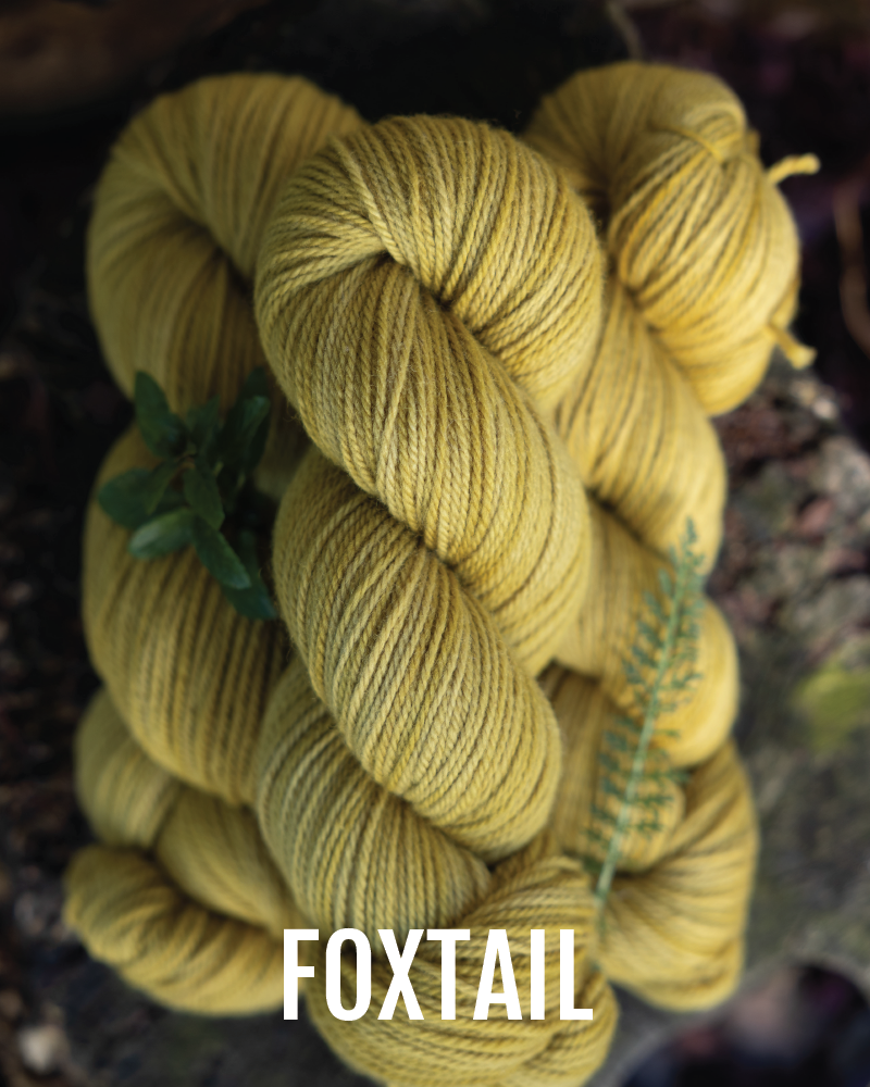 A stack of hand-dyed worsted weight  yarn in a gold ochre